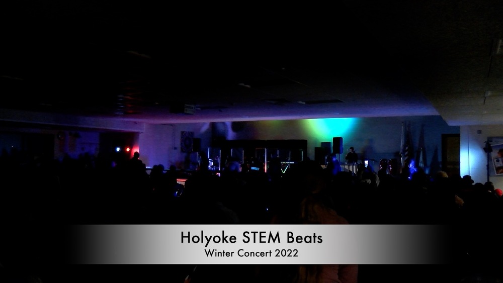 STEM Beats musicians are silhouetted on stage with colored lights