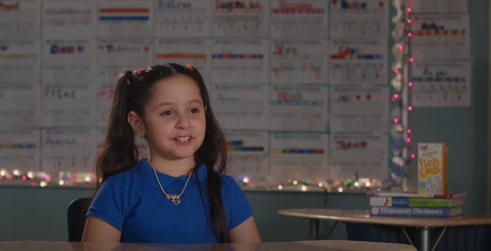Young student in blue shirt sitting down in a classroom .