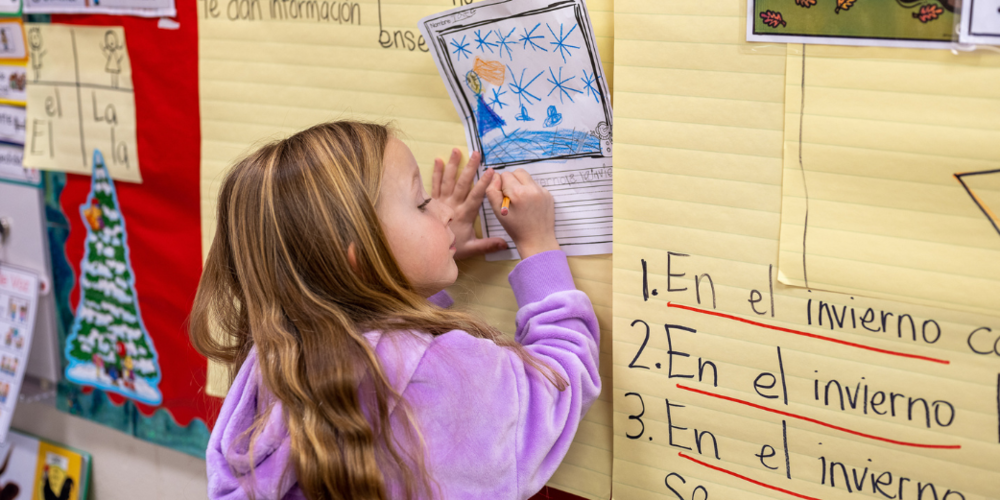 Elementary aged student taking notes in from the board. 