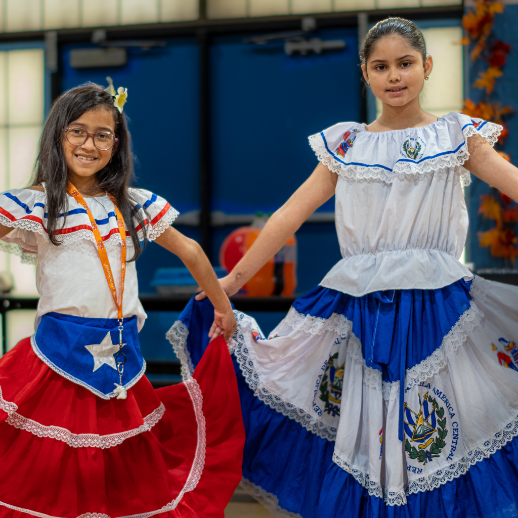 two students posing in their cultural dresses for Hispanic Heritage Month 