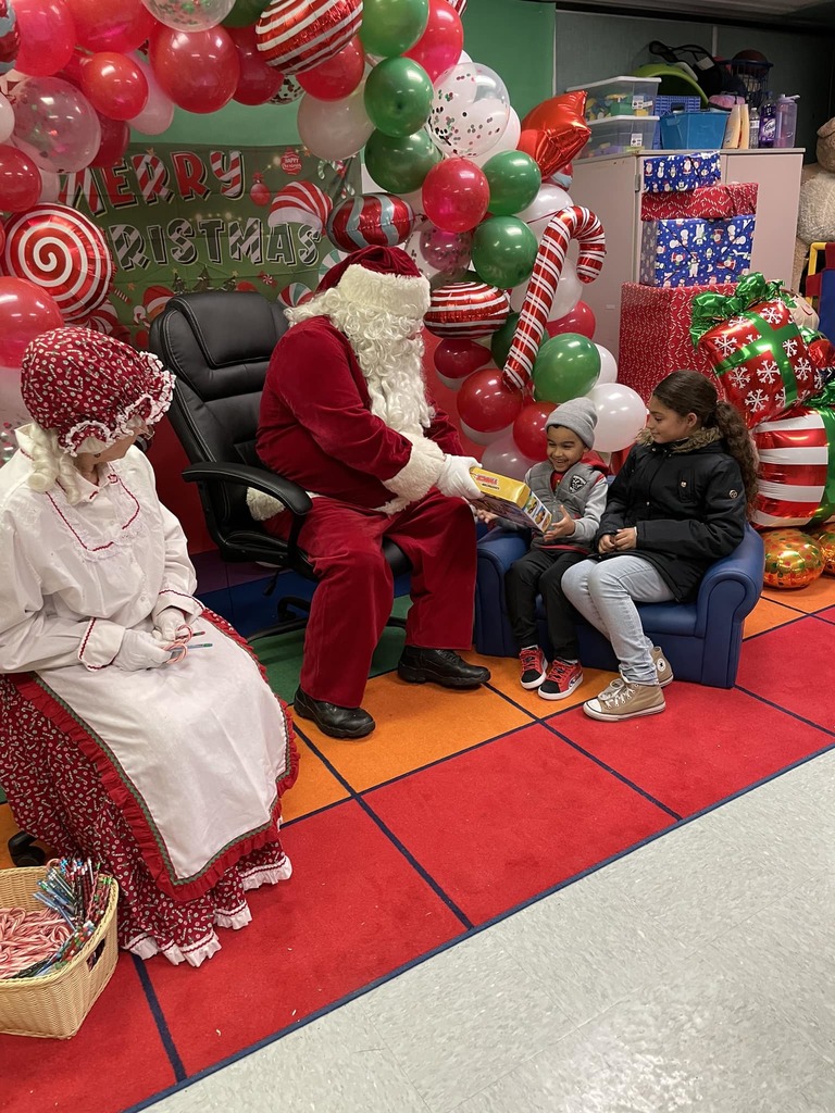 Santa and Mrs. Claus handing out toys to two students.