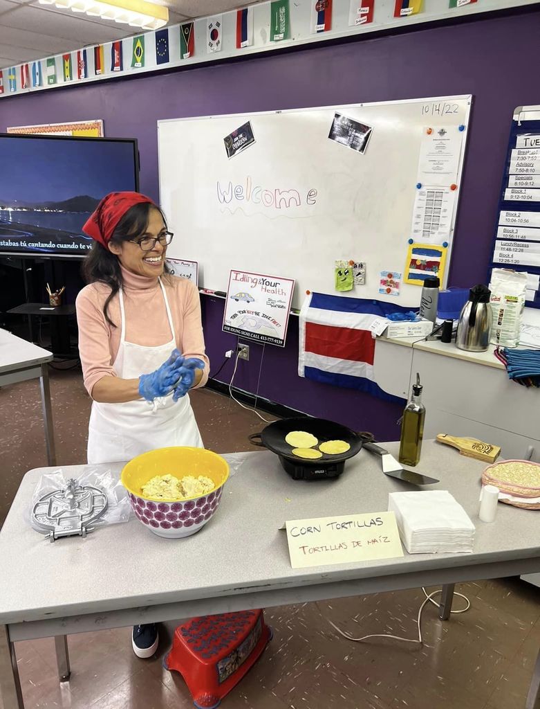 Picture of educator smiling while making food in a classroom. 