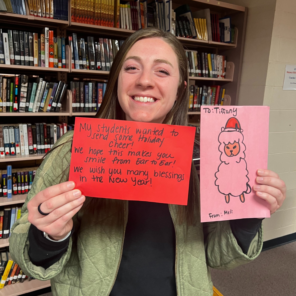 Teacher smiling while holding Christmas cards. 