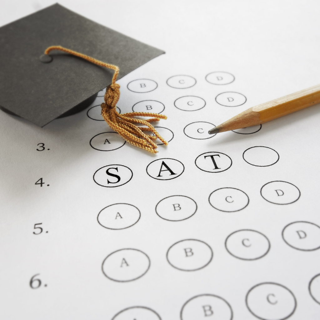 a graduation cap and a pencil sitting on top of an exam with the word SAT.