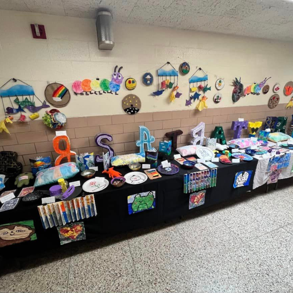 Assorted table with creative projects made by children. On the wall are hung up papercrafts.