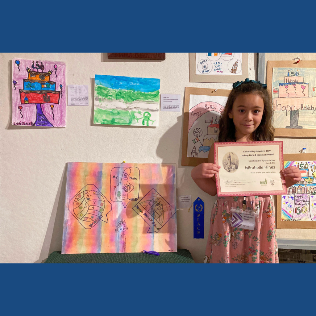 Picture of Mirabelle Hines holding a certficate in front of her artwork.