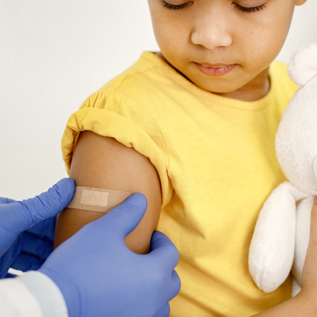 Picture of a kid getting a band aid in the shoulder 